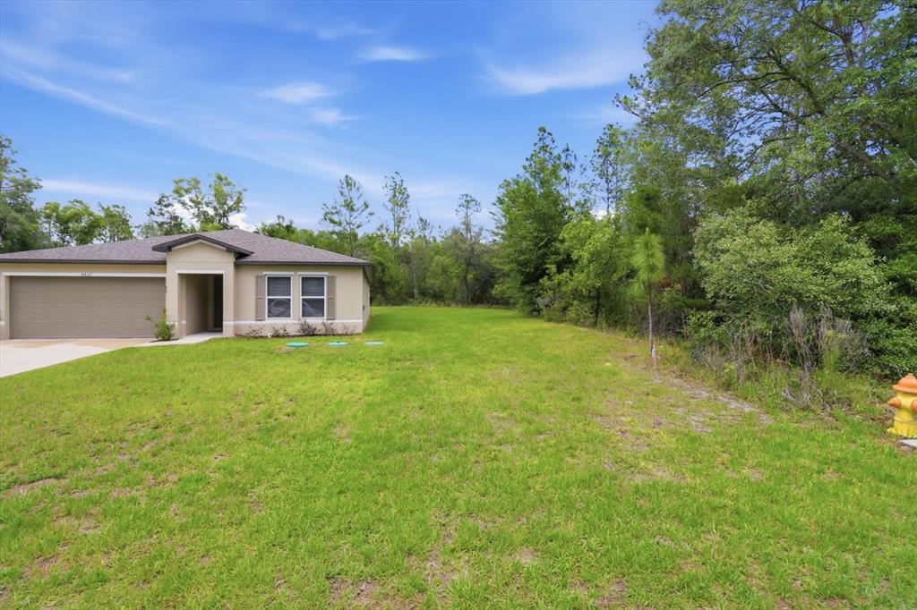 A single-story house with a two-car garage and a concrete driveway sits on a lot — 8827 N VIENNA DRIVE, DUNNELLON, FL