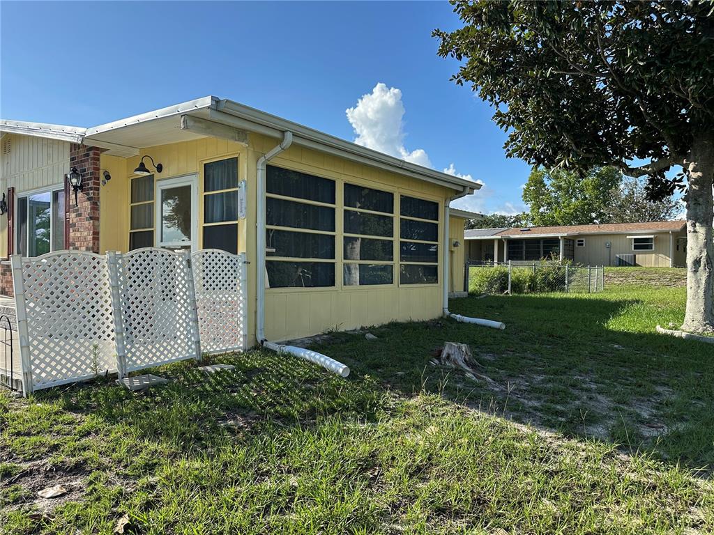 A yellow mobile home features a screened-in porch and a white lattice privacy fence — 9050 SW 101 ST LANE, OCALA, FL