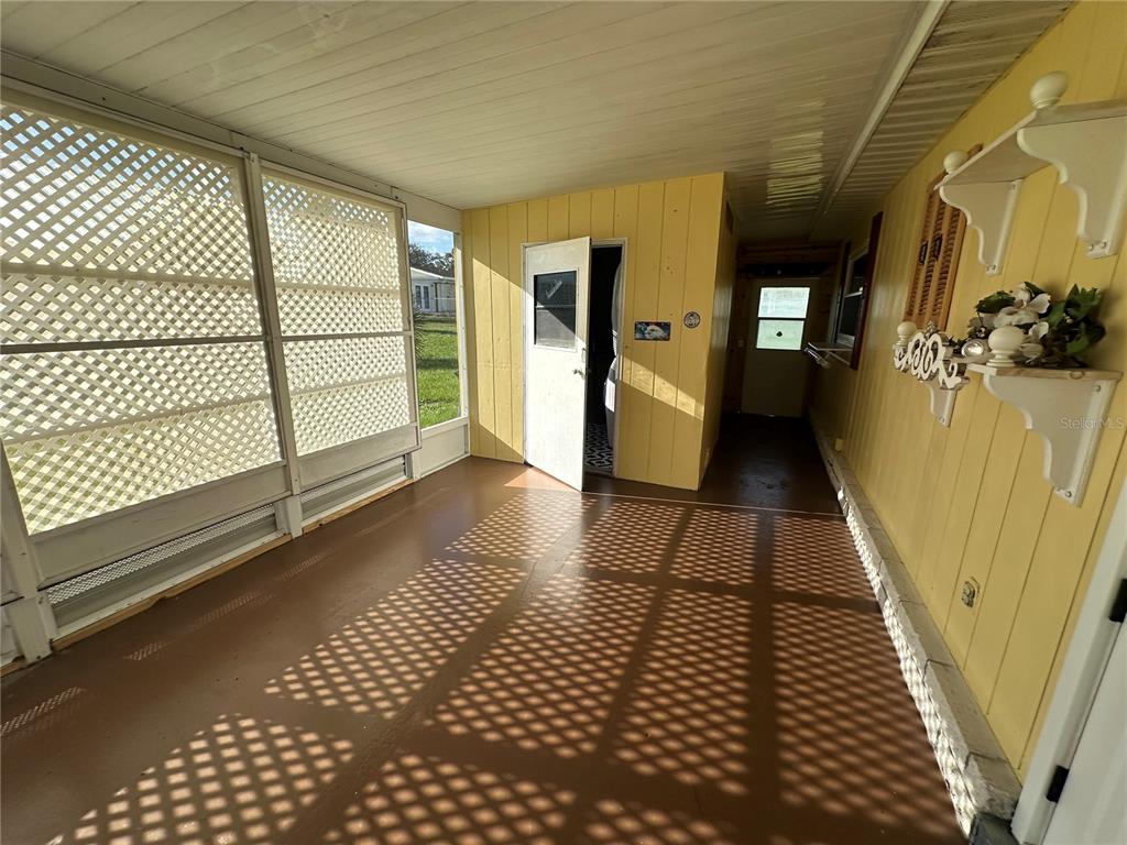 A covered porch features yellow paneled walls, a brown floor, and white lattice screen walls — 9050 SW 101 ST LANE, OCALA, FL