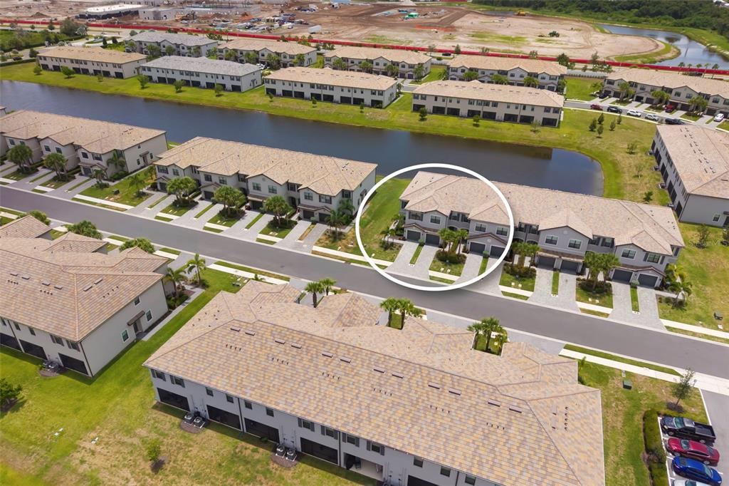 An aerial view shows a residential neighborhood with multi-unit townhomes surrounding a central pond — 15030 SUNNY DAY DRIVE, BRADENTON, FL