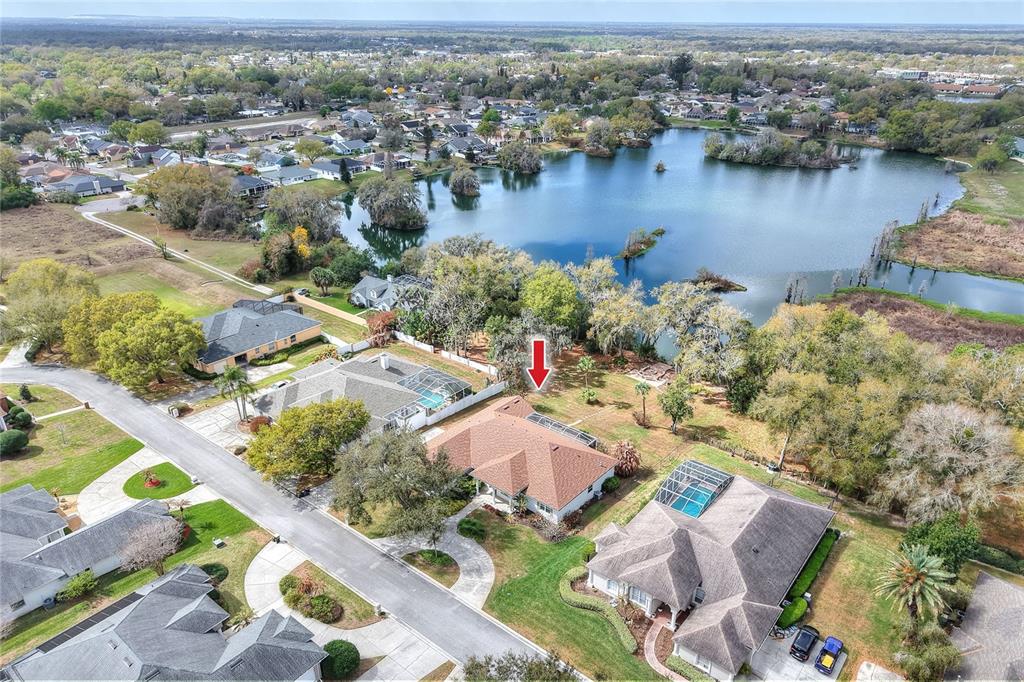 An aerial view shows a suburban house with a pool and a red arrow — 858 HANOVER WAY, LAKELAND, FL