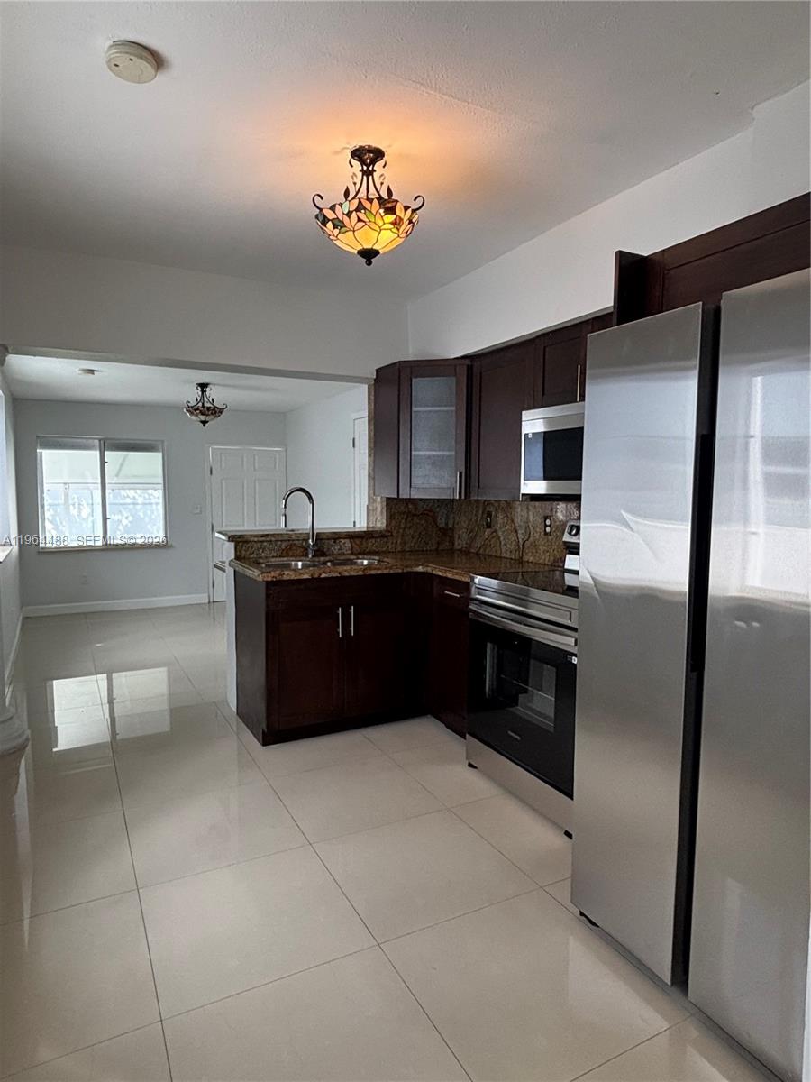 A kitchen with dark wood cabinets, granite countertops, and stainless steel appliances — 6823 SW 25th St, Miami FL 33155, MIAMI, FL