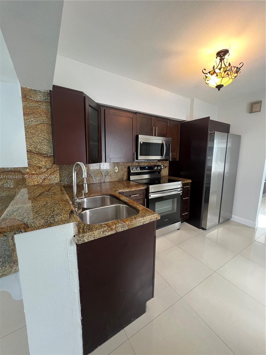 A kitchen features dark wood cabinets, granite countertops, stainless steel appliances, and a stained-glass light fixture — 6823 SW 25th St, Miami FL 33155, MIAMI, FL