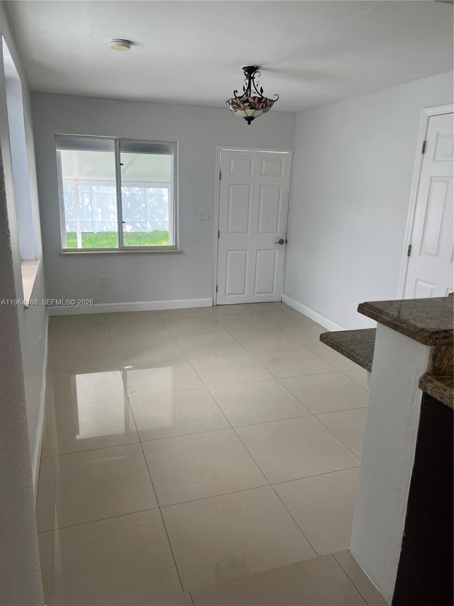 A dining area features light gray walls, beige tile flooring, and a decorative ceiling light — 6823 SW 25th St, Miami FL 33155, MIAMI, FL