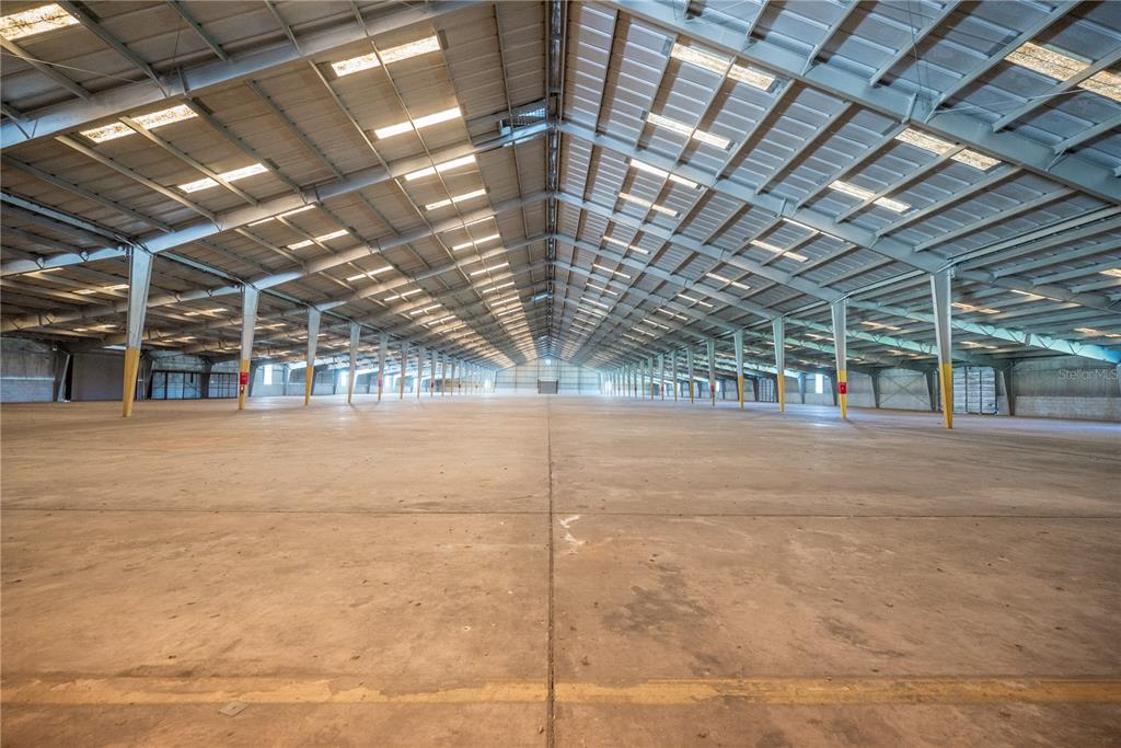 A large, empty industrial warehouse features a concrete floor and a high metal-truss ceiling — 14281 US HWY 301, STARKE, FL