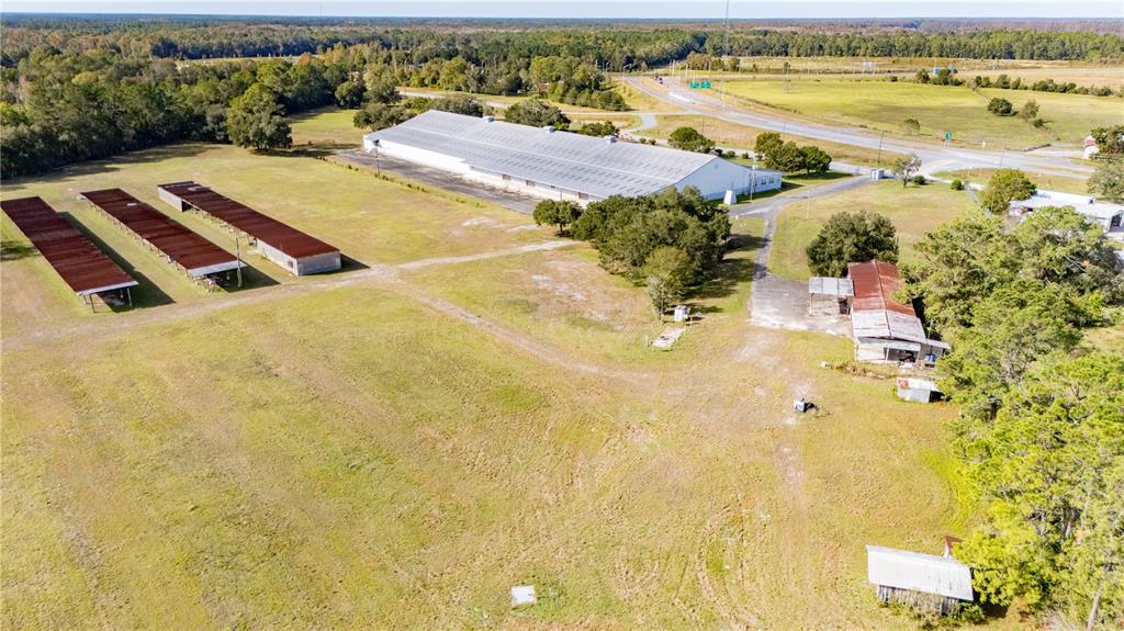 An aerial view shows a large warehouse, several open-sided sheds, and smaller outbuildings on land — 14281 US HWY 301, STARKE, FL