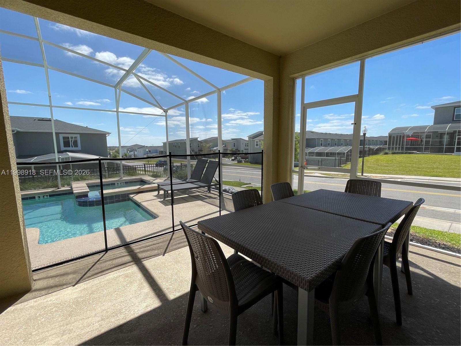 A screened-in patio features a dining set, a small pool, and a view of neighborhood houses — OTHER CITY - IN THE STATE OF FLORIDA, FL