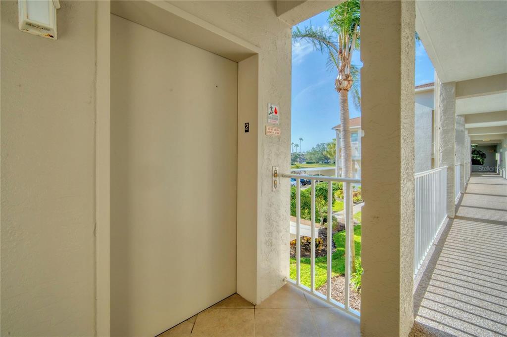 An elevator door with a number two sign is located on an outdoor apartment walkway — 9610 CLUB SOUTH CIRCLE UNIT # 4207, SARASOTA, FL