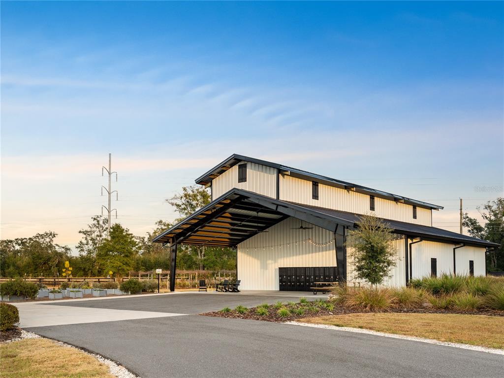 A modern white metal barn with a large covered patio and black structural framing — Lot 39 SW 124TH WAY, ARCHER, FL