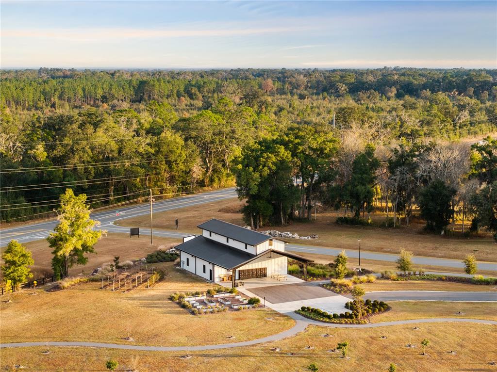 An aerial view of a modern white barn-style building with a black roof near a road — Lot 39 SW 124TH WAY, ARCHER, FL