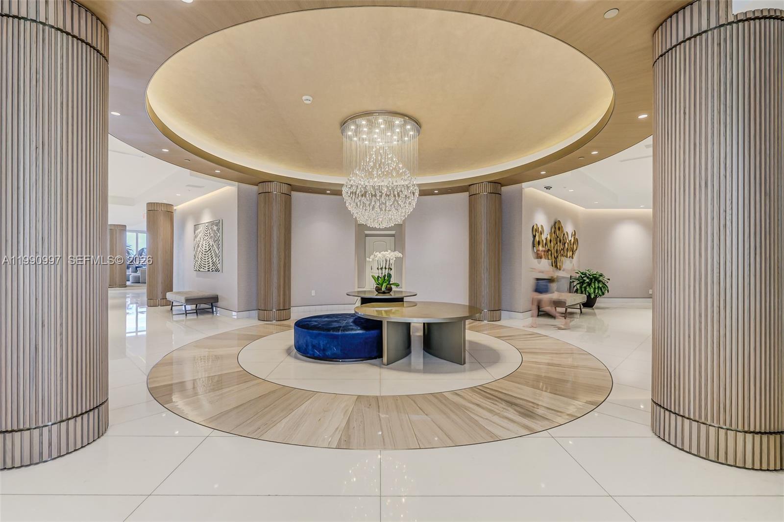 A modern lobby features a circular ceiling cove, a crystal chandelier, and fluted wooden columns — 888 Brickell Key Dr # 807, Miami FL 33131, MIAMI, FL