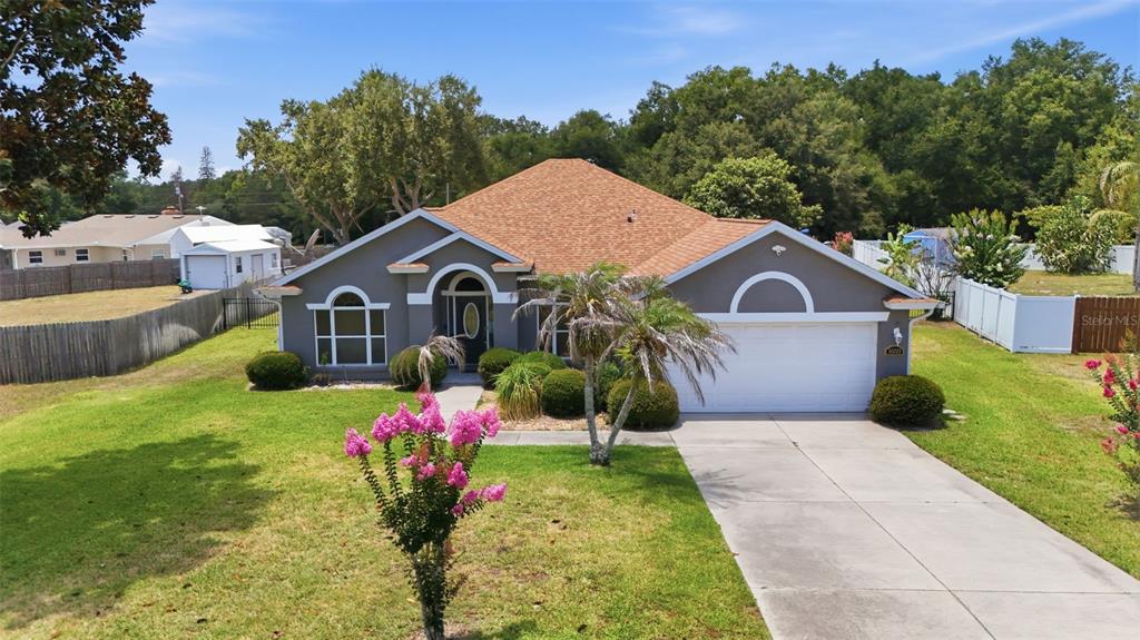 A single-story house with a gray exterior, a brown roof, and a concrete driveway — 36723 SUNDANCE DRIVE, GRAND ISLAND, FL