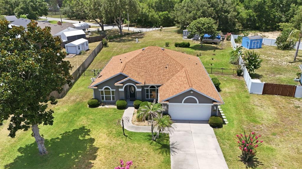 An aerial view of a single-story house with a brown roof and a concrete driveway — 36723 SUNDANCE DRIVE, GRAND ISLAND, FL