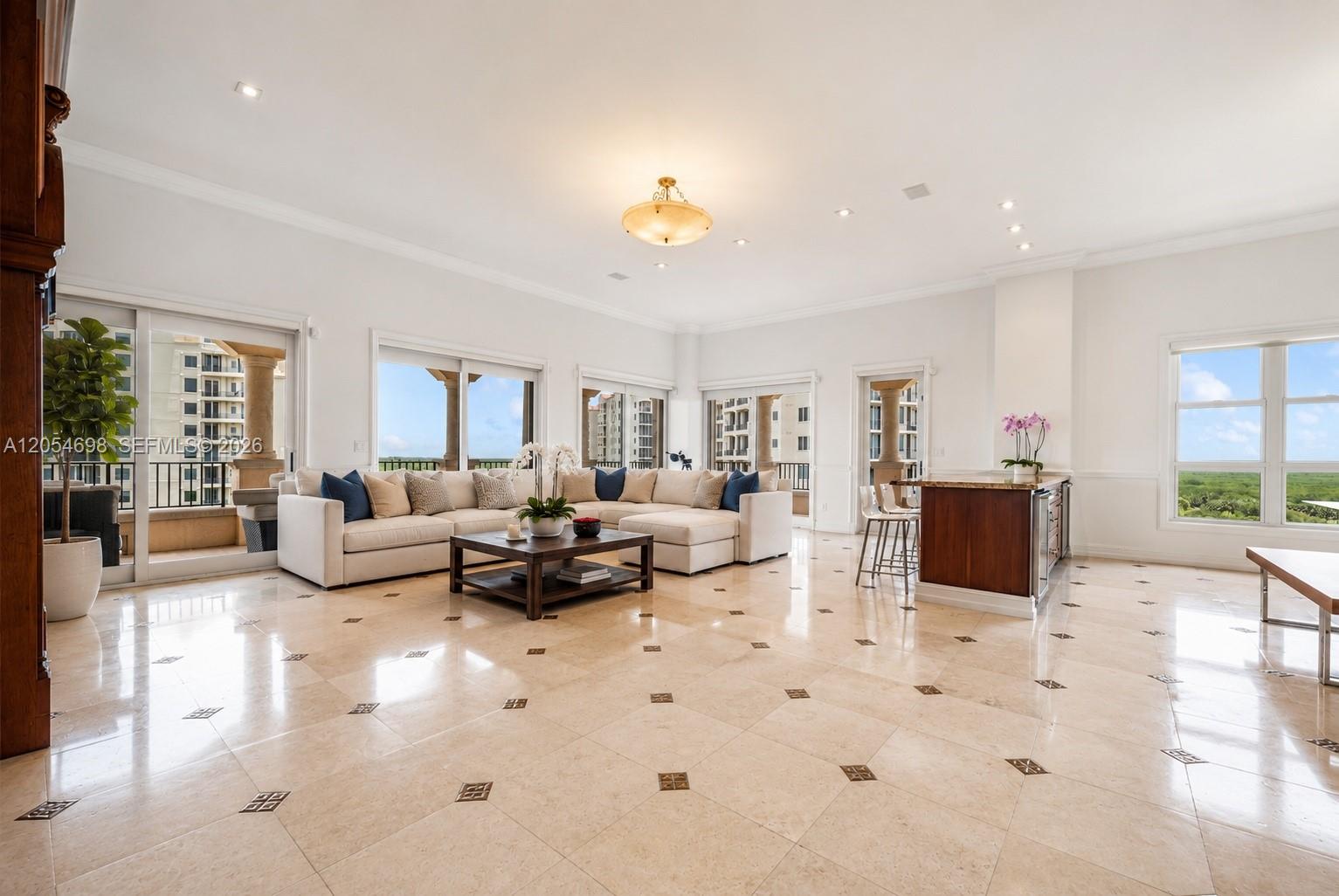 A spacious living room features light tile floors, a large sectional sofa, and balcony access — 13633 Deering Bay Dr, Coral Gables FL 33158, CORAL GABLES, FL