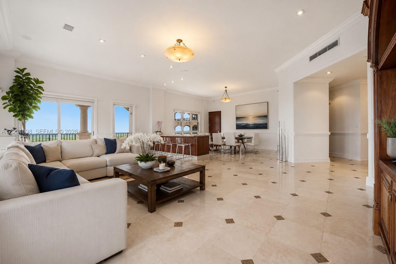 A spacious open-concept living and dining area features light tile flooring and a large sectional — 13633 Deering Bay Dr, Coral Gables FL 33158, CORAL GABLES, FL