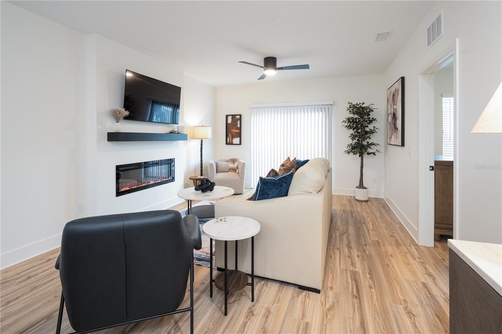A living room features a fireplace, a television, a sofa, and light wood-look flooring — 419 SE 1ST AVENUE UNIT 101, OCALA, FL