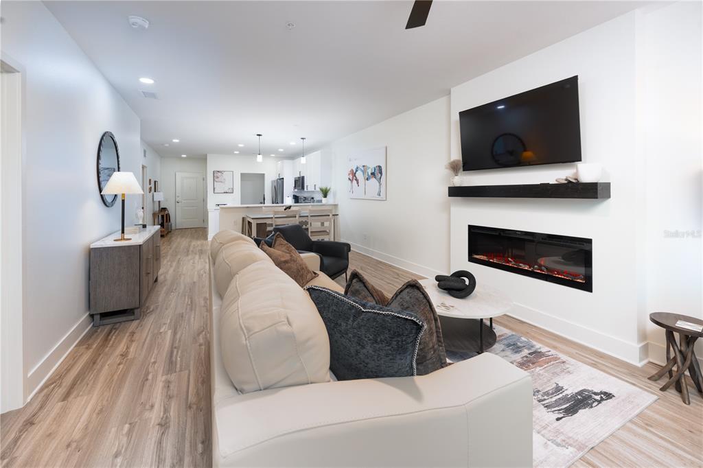 A living room features a fireplace, wall-mounted television, light wood flooring, and an open kitchen — 419 SE 1ST AVENUE UNIT 101, OCALA, FL