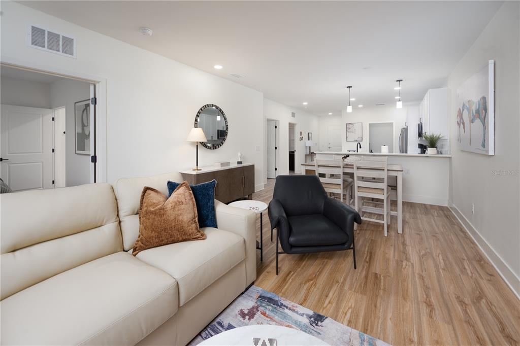 A living room with a cream sofa, black armchair, and an open kitchen in the background — 419 SE 1ST AVENUE UNIT 101, OCALA, FL