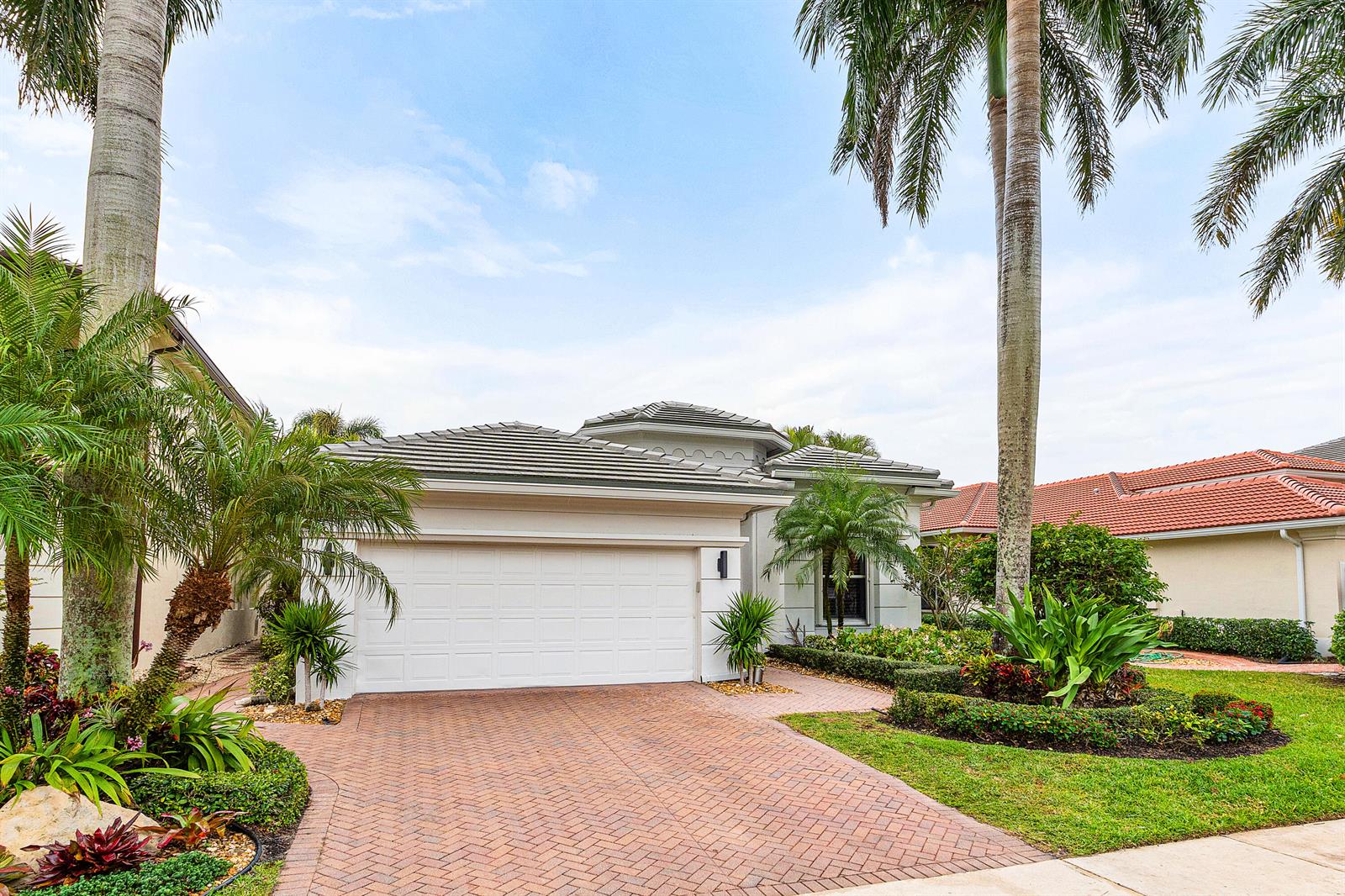 A single-story house with a white garage, brick driveway, and palm trees in the front — 15856 Double Eagle Trail, Delray Beach FL 33446, DELRAY BEACH, FL