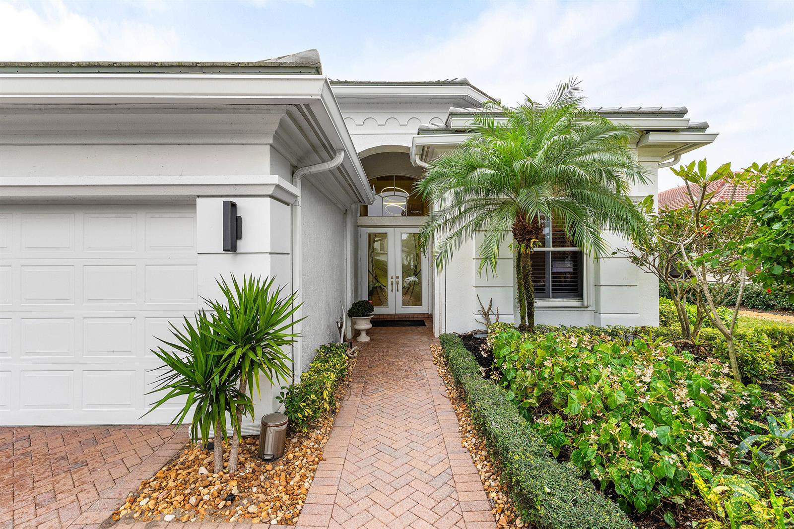 The exterior of a white house features a brick walkway, a palm tree, and landscaping — 15856 Double Eagle Trail, Delray Beach FL 33446, DELRAY BEACH, FL