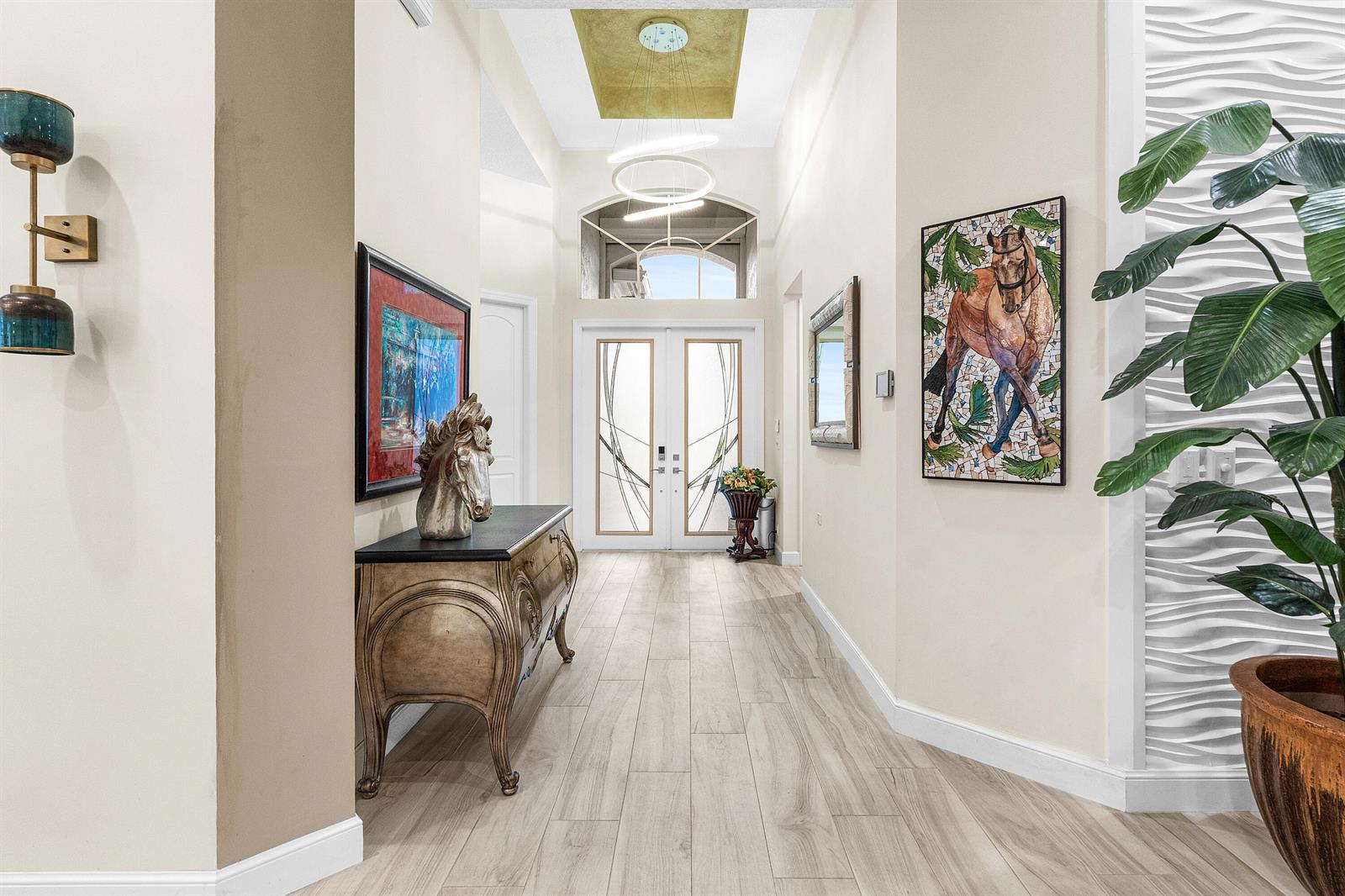 A bright entryway features a wood-look tile floor, a decorative console table, and modern lighting — 15856 Double Eagle Trail, Delray Beach FL 33446, DELRAY BEACH, FL
