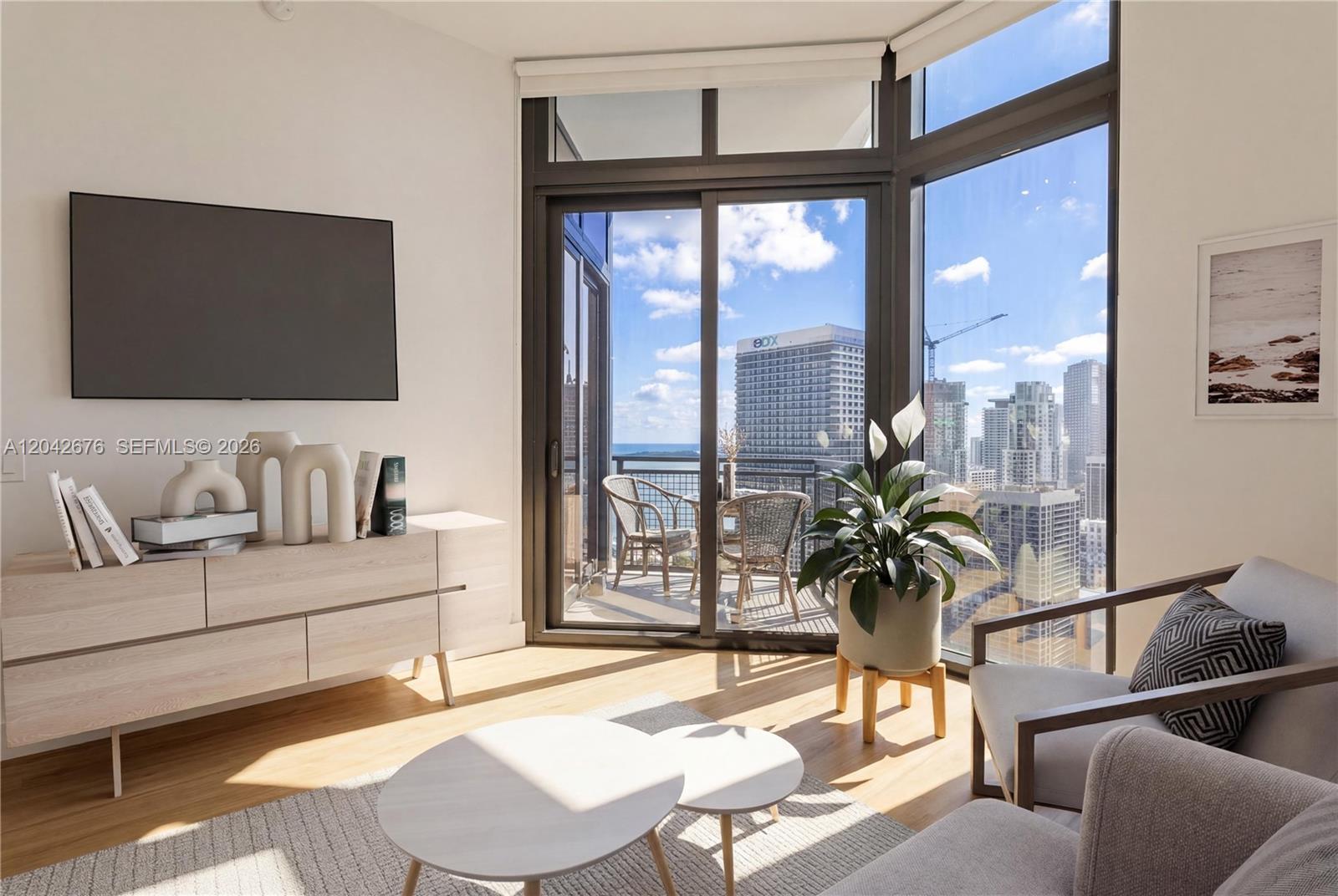 A modern living room features light wood floors, a balcony, and floor-to-ceiling city views — 650 NE 2nd Ave # 3504, Miami FL 33132, MIAMI, FL