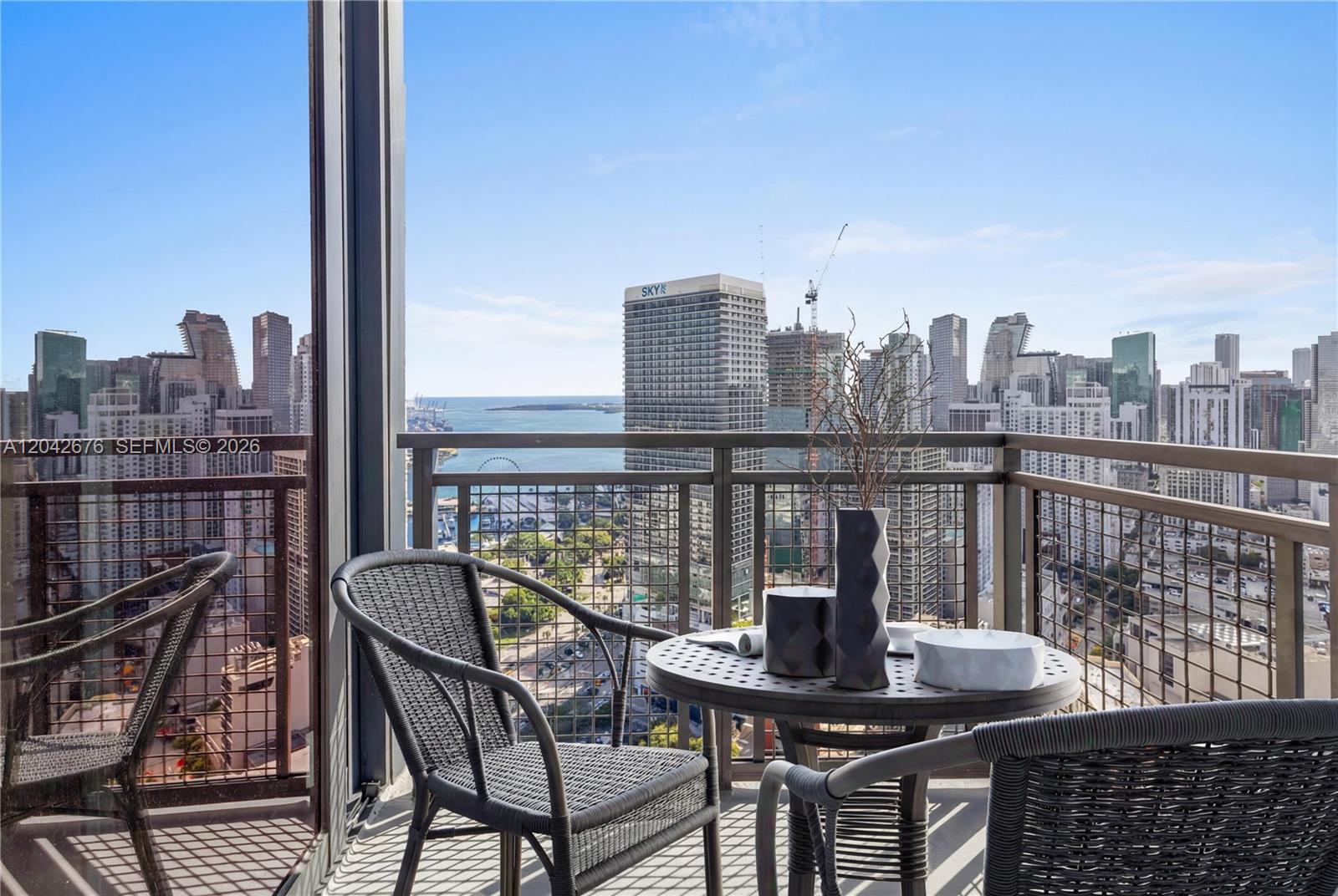 A balcony with outdoor furniture overlooks a city skyline and a body of water — 650 NE 2nd Ave # 3504, Miami FL 33132, MIAMI, FL