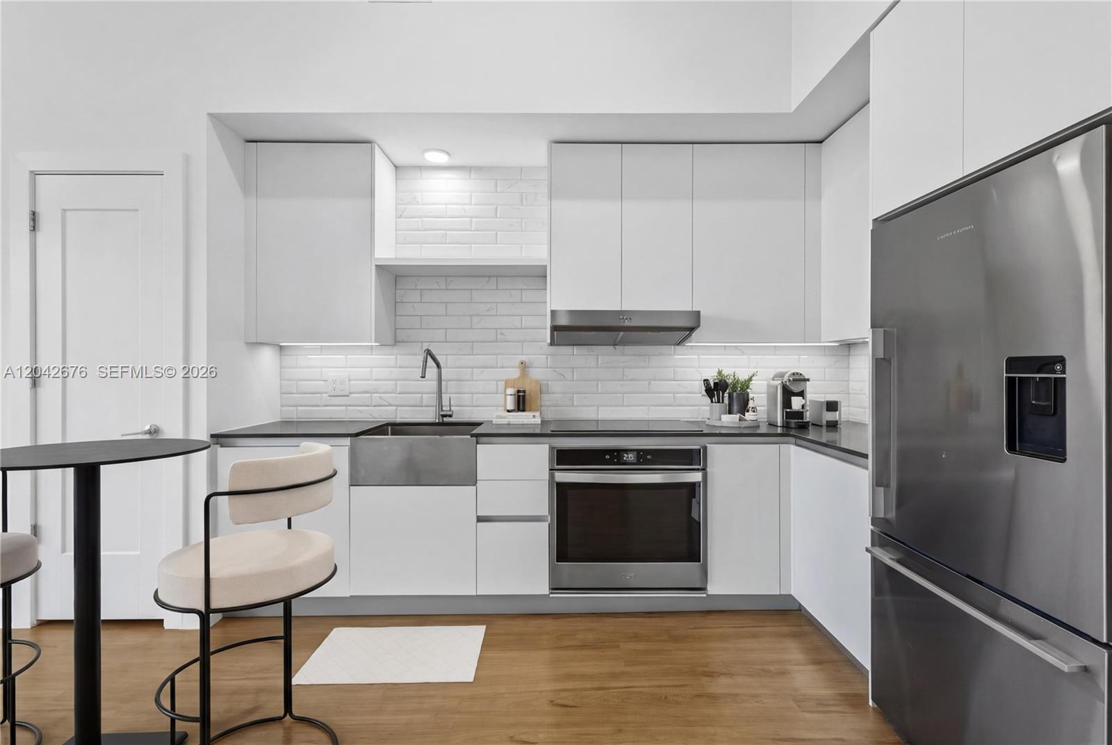 A modern kitchen features white cabinetry, a stainless steel farmhouse sink, and wood flooring — 650 NE 2nd Ave # 3504, Miami FL 33132, MIAMI, FL