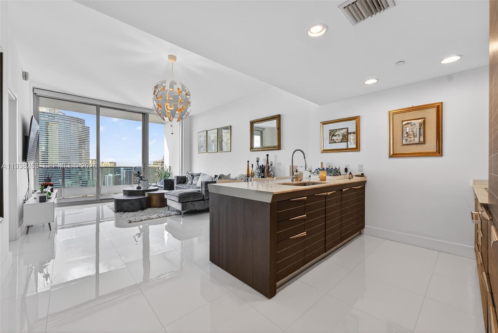 A modern kitchen island with dark wood cabinets sits in an open-concept living space — 200 Biscayne Boulevard Way # 4414, Miami FL 33131, MIAMI, FL