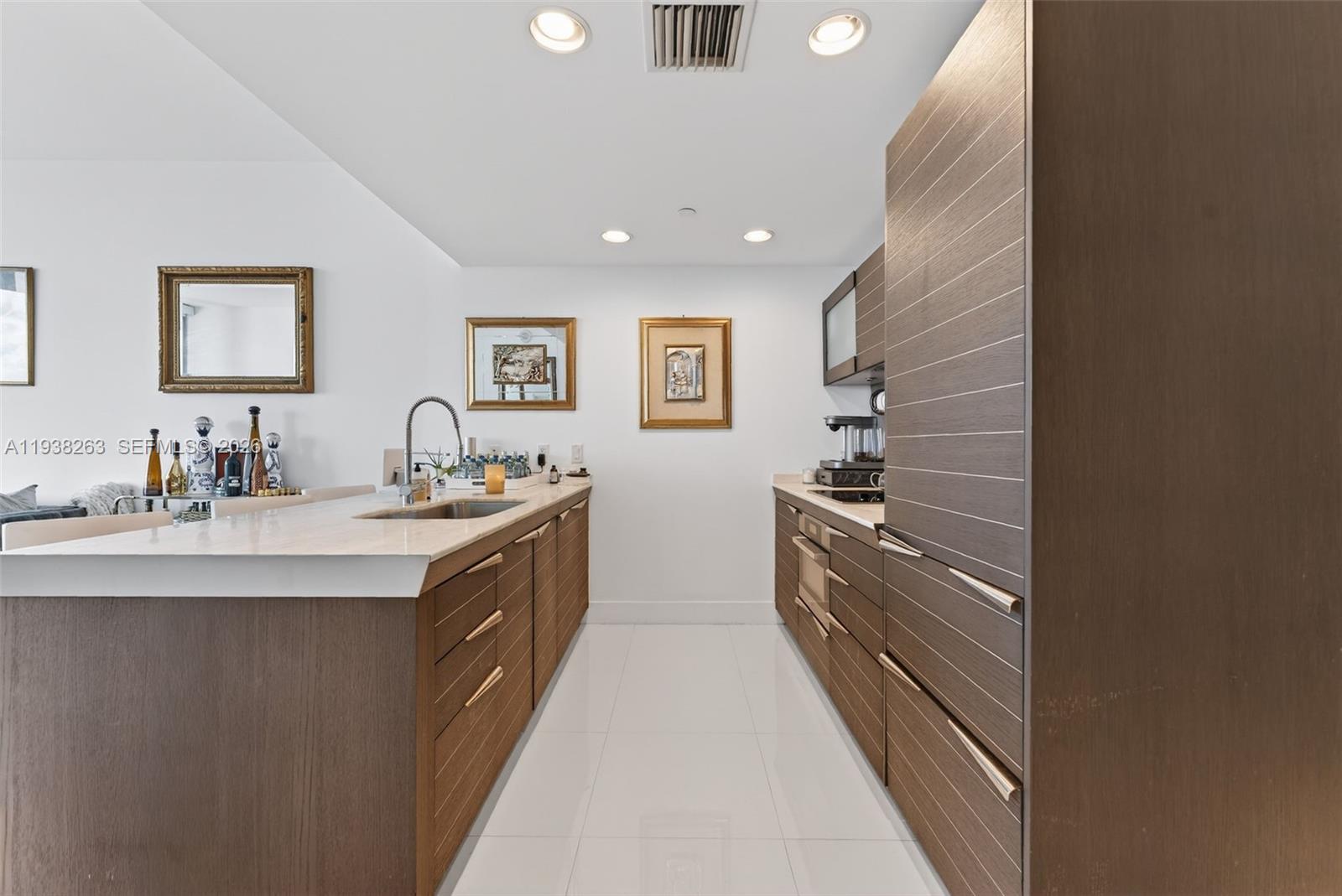 A modern kitchen features wood-grain cabinetry, white countertops, and white tile flooring — 200 Biscayne Boulevard Way # 4414, Miami FL 33131, MIAMI, FL