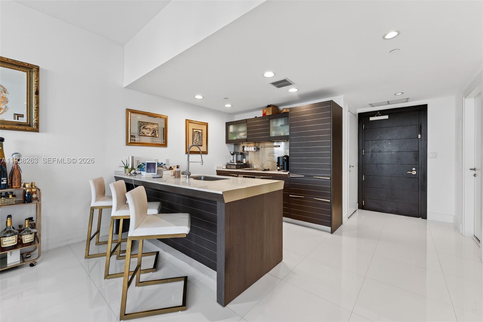 A modern kitchen features a stone-topped island with bar seating and dark wood cabinetry — 200 Biscayne Boulevard Way # 4414, Miami FL 33131, MIAMI, FL