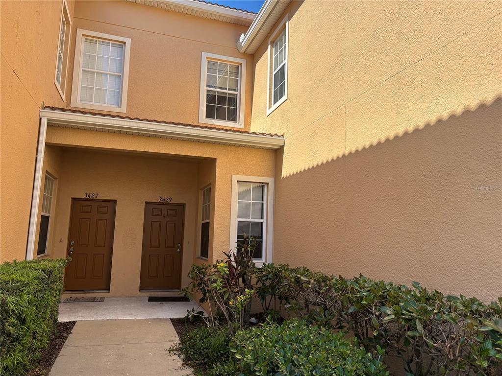 The exterior of a two-story tan stucco building features two adjacent brown front doors — 3429 PARKRIDGE CIRCLE UNIT 19-103, SARASOTA, FL