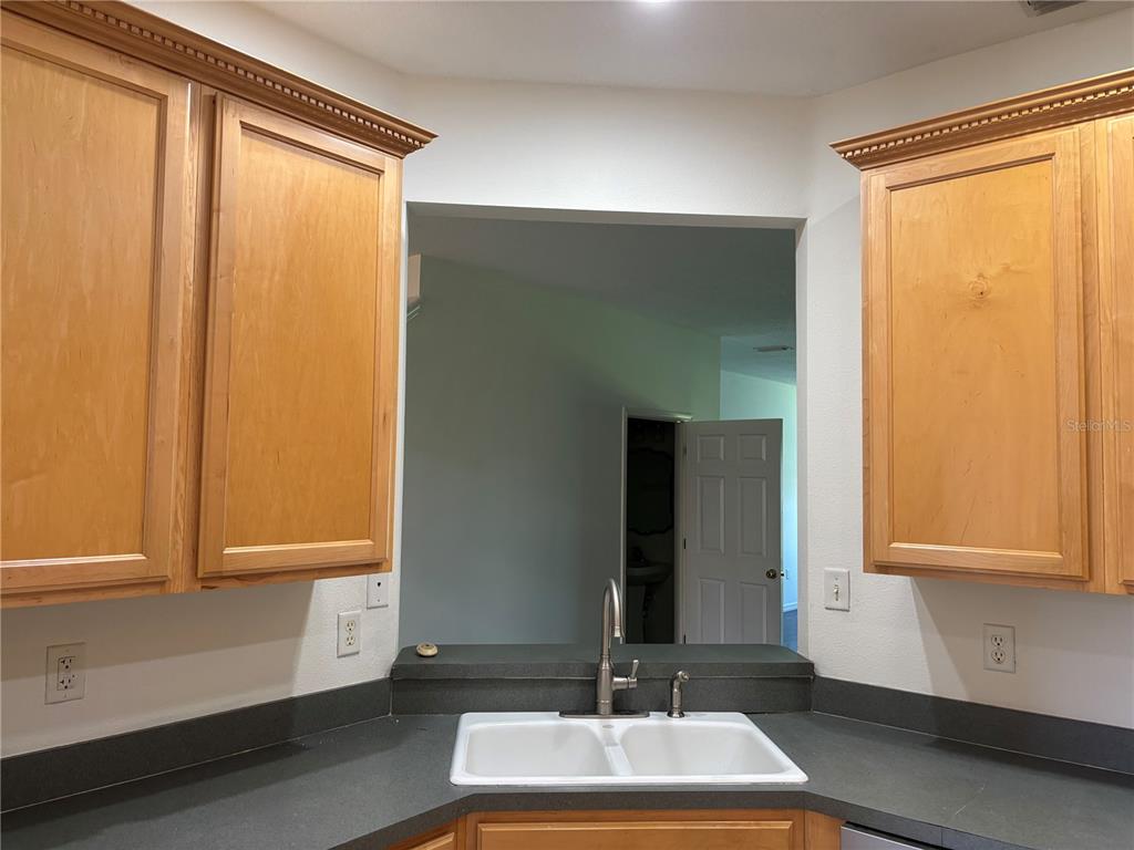 A kitchen sink area features light wood cabinets, a dark countertop, and a pass-through window — 3429 PARKRIDGE CIRCLE UNIT 19-103, SARASOTA, FL