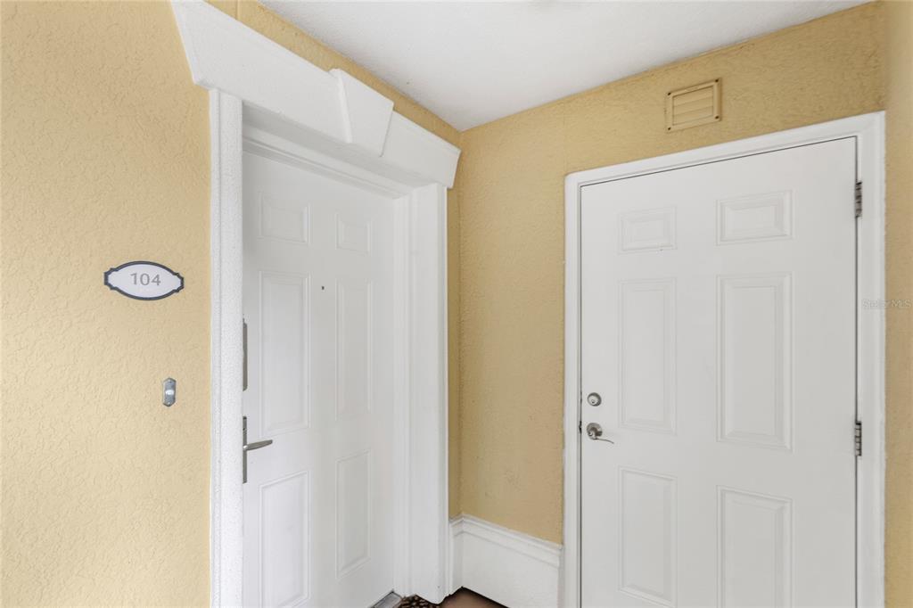 Two white doors are set into a beige wall in an apartment building hallway — 7650 WHISPER WAY UNIT 104, REUNION, FL