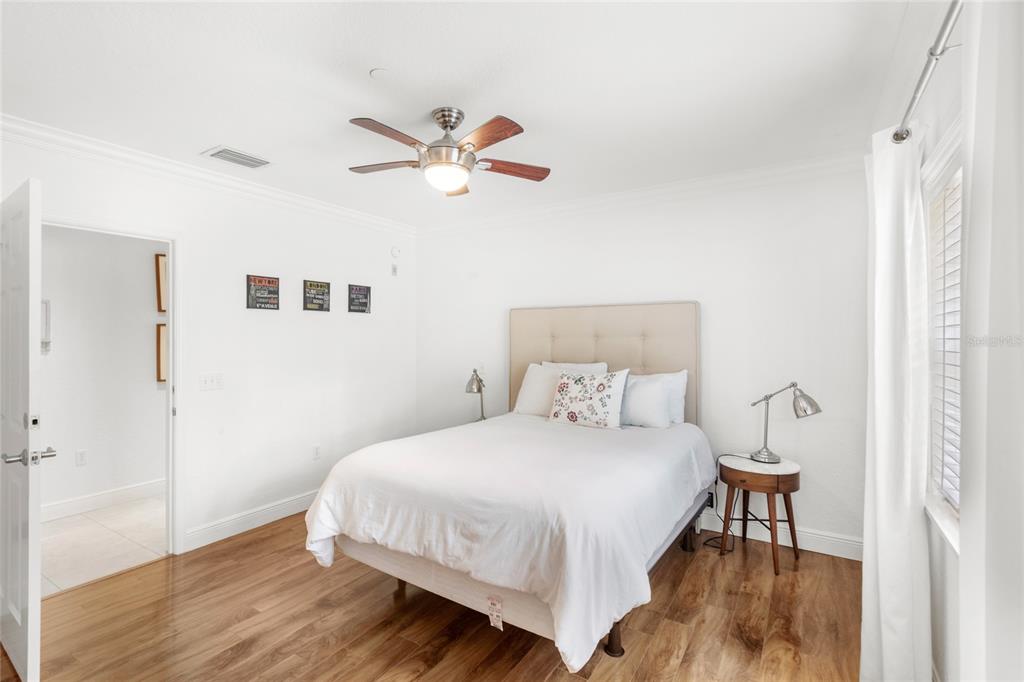 A bedroom with white walls, wood flooring, a queen bed, and a ceiling fan — 7650 WHISPER WAY UNIT 104, REUNION, FL