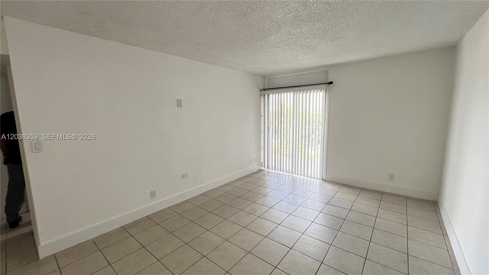 An empty room features white walls, light-colored tile flooring, and a sliding glass door — 4550 NW 9th St # 612E, Miami FL 33126, MIAMI, FL