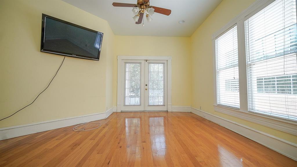 A room with yellow walls, hardwood floors, a ceiling fan, a wall-mounted television, and windows — 333 S PLANT AVENUE, TAMPA, FL