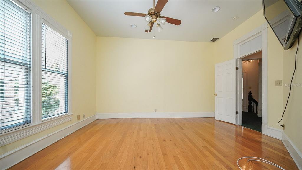 An empty room with light yellow walls, hardwood floors, a ceiling fan, and two windows — 333 S PLANT AVENUE, TAMPA, FL