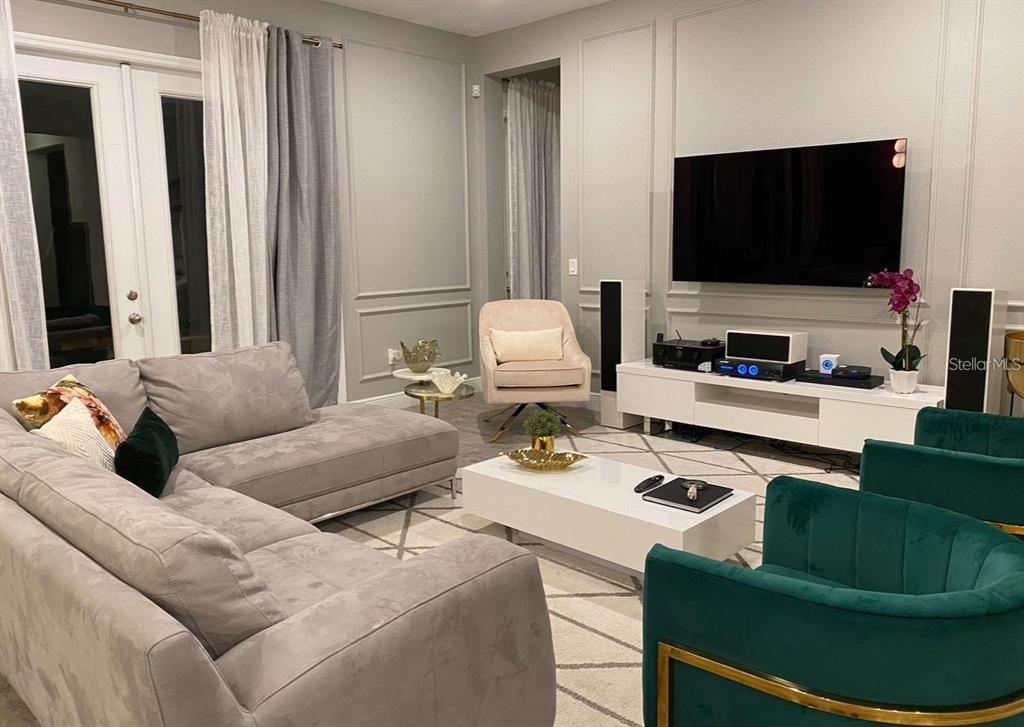 A living room features a grey sectional, two green velvet chairs, and a wall-mounted television — 14739 GLADE HILL PARK WAY, WINTER GARDEN, FL