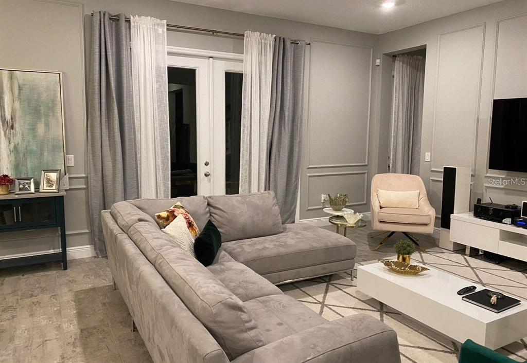 A living room features a gray sectional sofa, a white coffee table, and paneled walls — 14739 GLADE HILL PARK WAY, WINTER GARDEN, FL