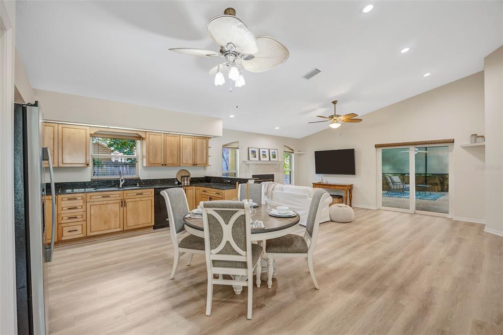An open-concept kitchen and dining area features light wood cabinets, dark countertops, and laminate flooring — 3015 FOLKLORE DRIVE, VALRICO, FL