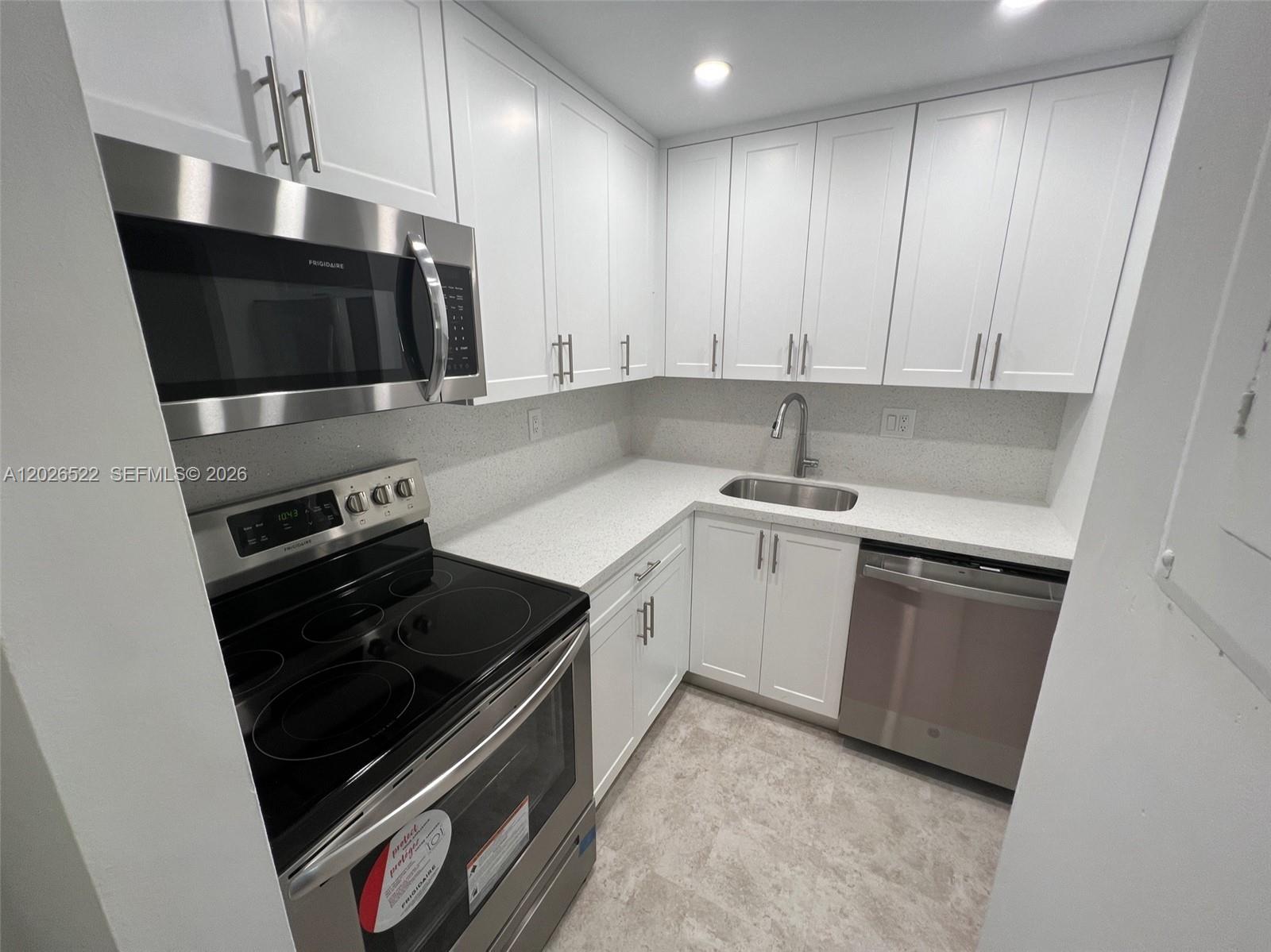 A modern kitchen features white cabinets, stainless steel appliances, and light-colored countertops — 10415 N Kendall Dr # B113, Miami FL 33176, MIAMI, FL
