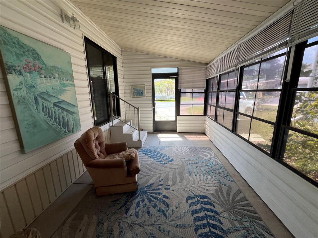 A sunroom features white paneled walls, a patterned area rug, a recliner, and large windows — 7392 INTERNATIONAL CIRCLE, LAKE WALES, FL