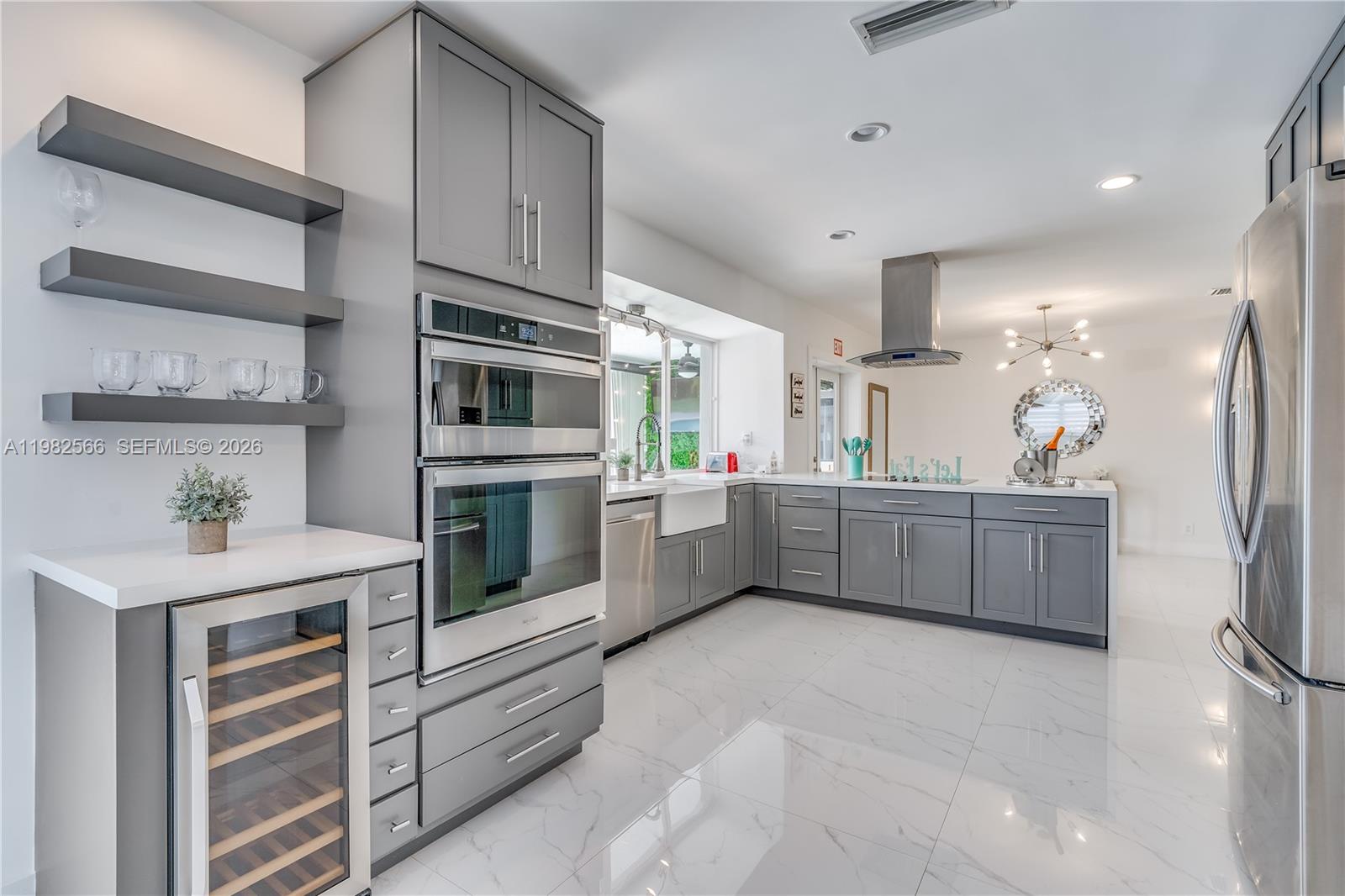 A modern kitchen features gray cabinetry, stainless steel appliances, white countertops, and white tile flooring — 4212 Van Buren St, Hollywood FL 33021, HOLLYWOOD, FL