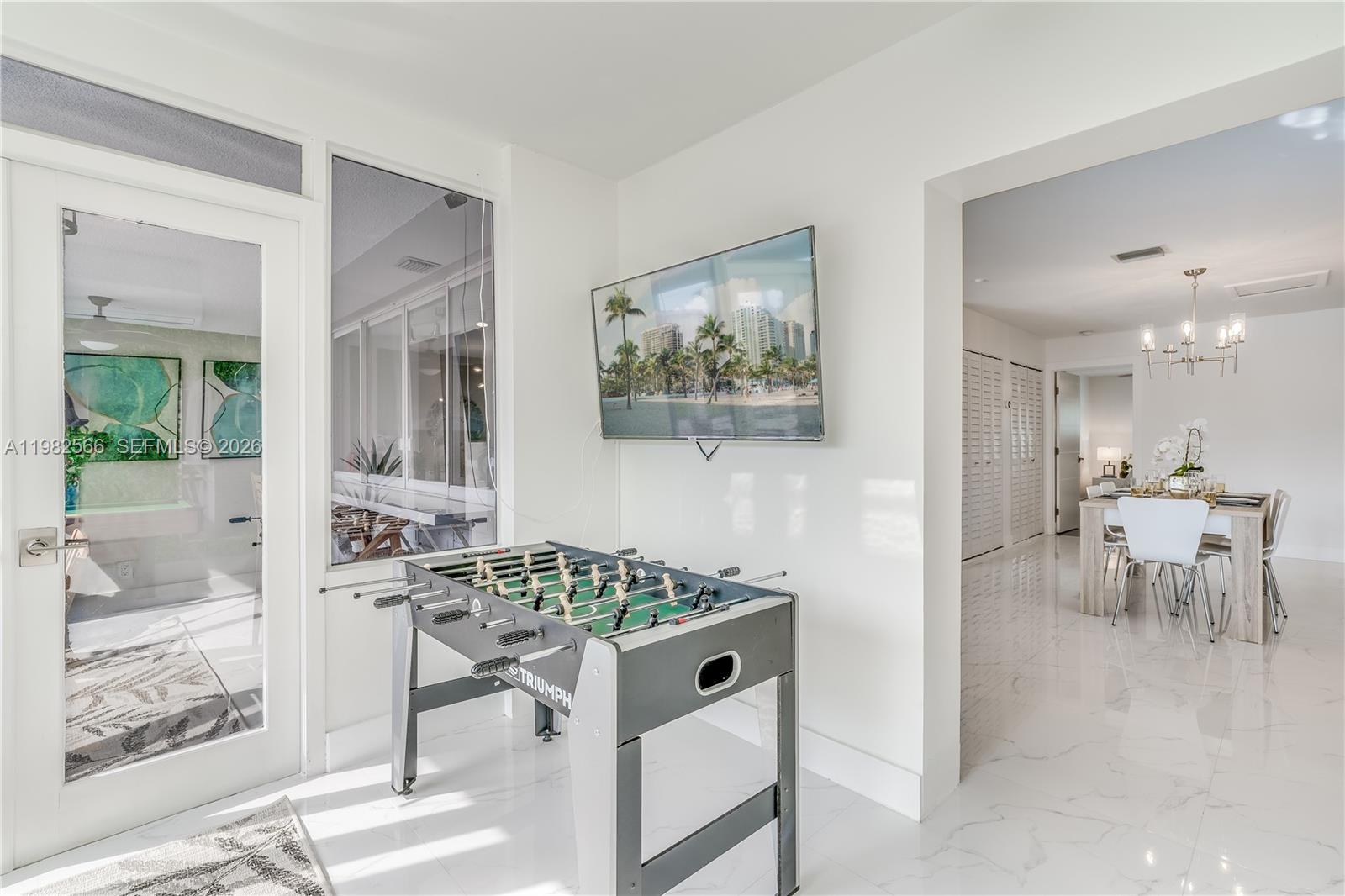 A game room features a foosball table, a wall-mounted television, and white tile flooring — 4212 Van Buren St, Hollywood FL 33021, HOLLYWOOD, FL