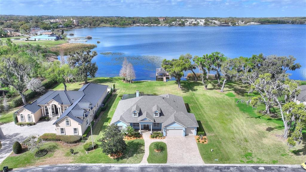 An aerial view shows two houses with shingled roofs situated on a large grassy lakefront lot — 4848 ISLAND SHORES LANE, LAKELAND, FL