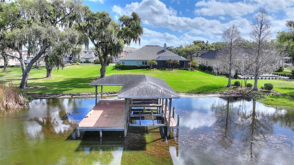 An aerial view shows a wooden boat dock on a pond behind a residential house — 4848 ISLAND SHORES LANE, LAKELAND, FL