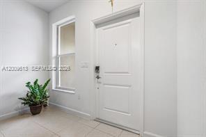 A white front door stands next to a window in a room with tiled floors — 2781 NW 55th Way, Lauderhill FL 33313, LAUDERHILL, FL