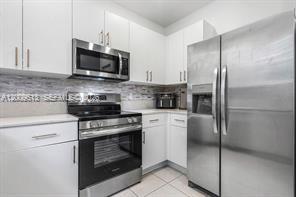 A modern kitchen features white cabinets, stainless steel appliances, and a tiled backsplash — 2781 NW 55th Way, Lauderhill FL 33313, LAUDERHILL, FL