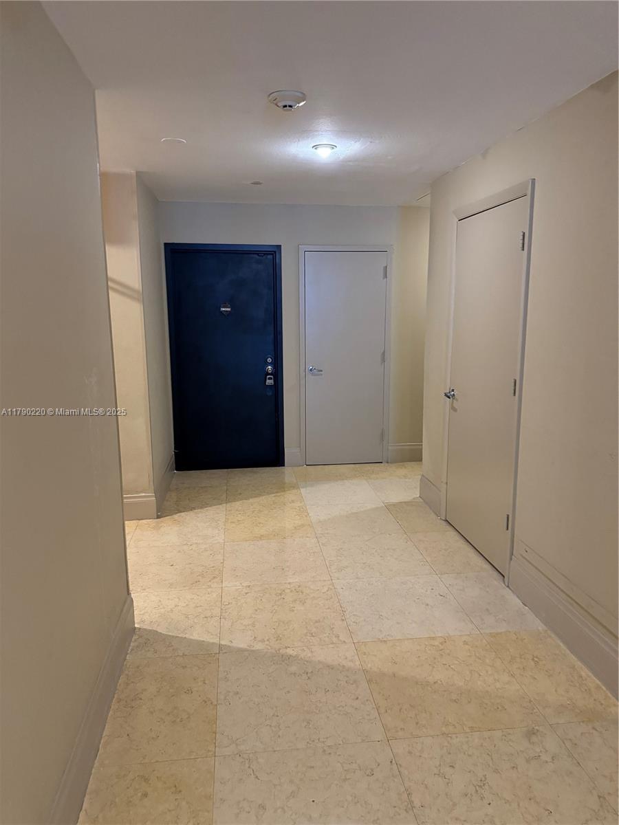 A hallway features light-colored tile flooring, beige walls, and three closed doors — 1420 Brickell Bay Dr, Miami FL 33131, MIAMI, FL